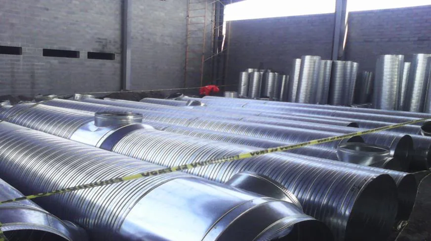 Patio con decenas de tramos de espiroducto galvanizado apilados junto a tes y conexiones fabricadas